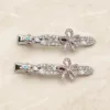 Conjunto de dois ganchos prateados com laço rosa e cristais multicolores