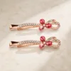 Conjunto de dois ganchos rosa-dourados com flor rosa e cristais multicolores