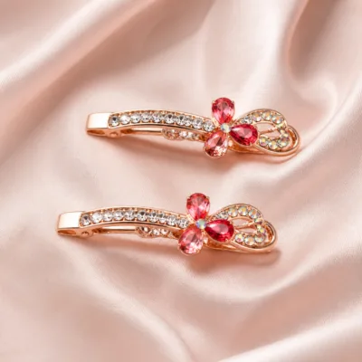 Par de ganchos rosa-dourados com ramo transparente e folha de cristais coloridos