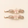 Conjunto de dois ganchos em ouro rosa com flor branca e cristais