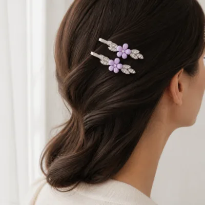 Dois ganchos prateados com flor lilás aplicados no cabelo