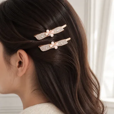 Dois ganchos ouro rosa com laço de cristais aplicados no cabelo