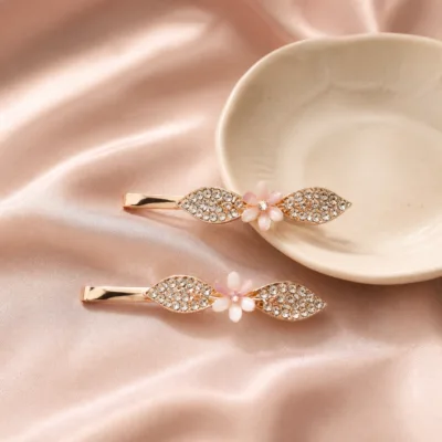 Dois ganchos ouro rosa com cristais sobre cetim rosa