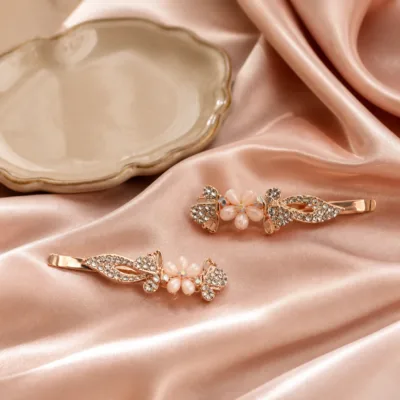 Dois ganchos ouro rosa com borboletas e flor sobre cetim rosa