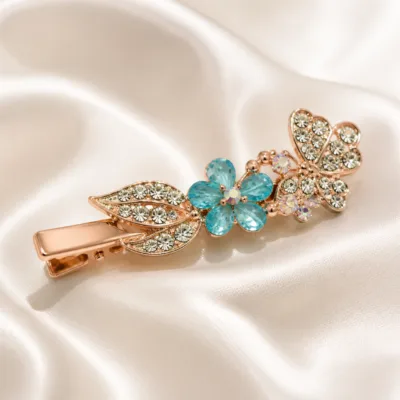 Detalhe de gancho ouro rosa com borboleta de cristais e flor turquesa