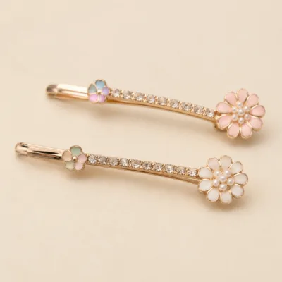 Detalhe de dois ganchos ouro rosa com cristais e flores coloridas