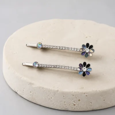 Dois ganchos prateados com flores multicolores sobre pedra clara