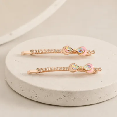 Dois ganchos ouro rosa com laço multicolor sobre pedra clara