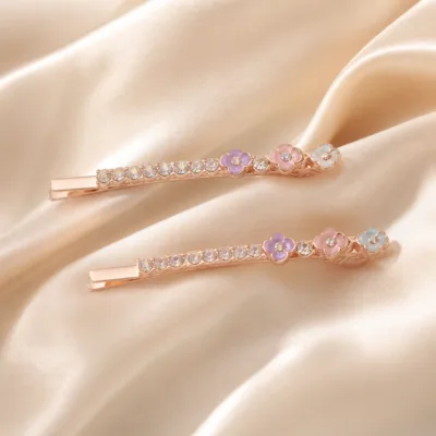 Conjunto de ganchos ouro rosa com detalhes coloridos sobre cetim