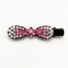Gancho de cabelo preto com laço de strass rosa em fundo branco