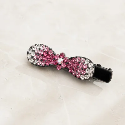 Gancho bico de pato com laço de strass rosa sobre pedra clara