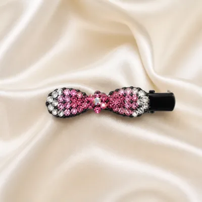 Gancho de cabelo preto com strass rosa sobre cetim marfim
