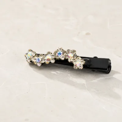 Gancho bico de pato com flores de strass sobre pedra clara