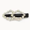 Gancho preto com duas flores de strass branco em fundo claro