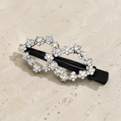 Gancho de cabelo preto com flores de strass sobre pedra bege