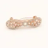 Gancho automático rosa-dourado com pérolas e strass em fundo branco