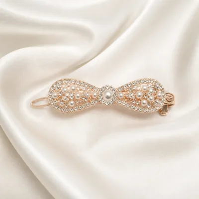 Gancho rosa-dourado com pérolas e strass sobre cetim marfim