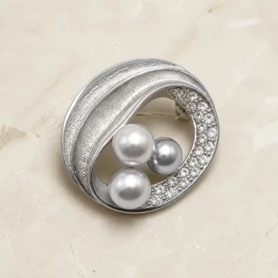 Broche oval prateado com três pérolas cinzentas e cristais