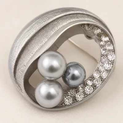 Pormenor das pérolas cinzentas e da faixa de cristais do broche