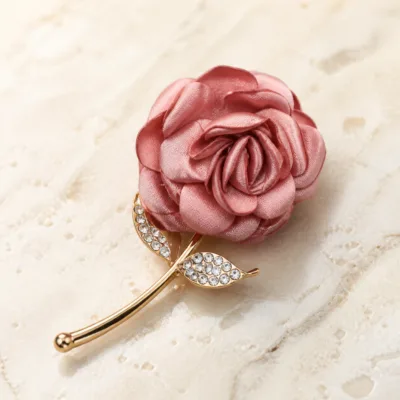Broche rosa de cetim com haste dourada e folhas de cristais