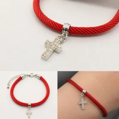 Detalhe da cruz prateada com cristais e do cordão vermelho