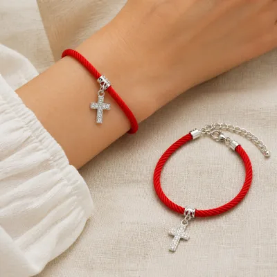 Pulseira vermelha com cruz de cristais usada no pulso