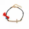 Pulseira preta com cruz dourada, cristais, borla vermelha e conta azul