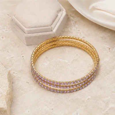 Pulseiras douradas com cristais lilás em composição elegante
