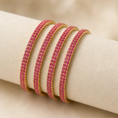 Quatro pulseiras douradas com cristais rosa num expositor