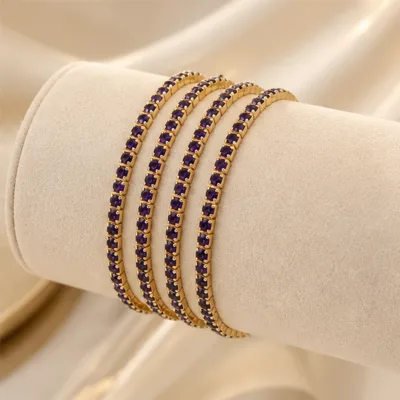 Quatro pulseiras douradas com cristais roxos num expositor