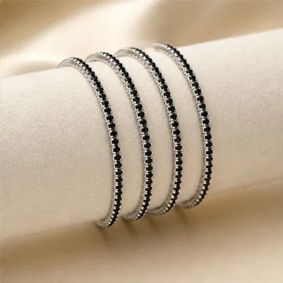 Quatro pulseiras prateadas com cristais pretos num expositor