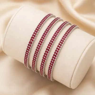 Quatro pulseiras prateadas com cristais vermelhos num expositor