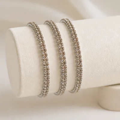 Quatro pulseiras prateadas com cristais champanhe num expositor