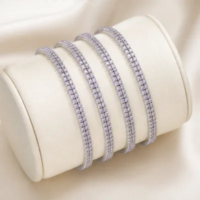 Quatro pulseiras prateadas com cristais lilás num expositor