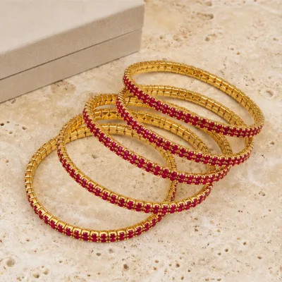 Pulseiras douradas com cristais vermelhos em composição elegante