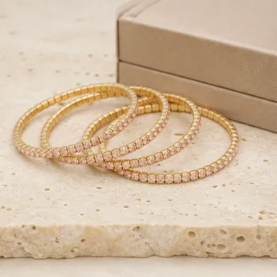 Pulseiras douradas com cristais rosa-claro numa composição elegante