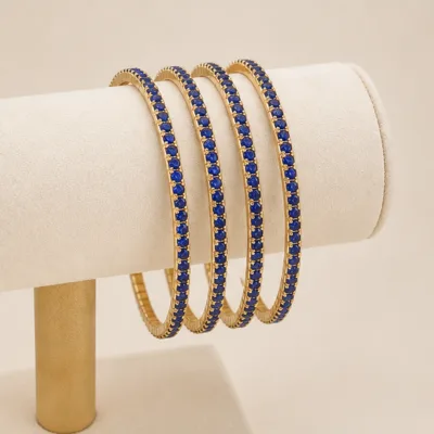 Quatro pulseiras douradas com cristais azul-royal num expositor