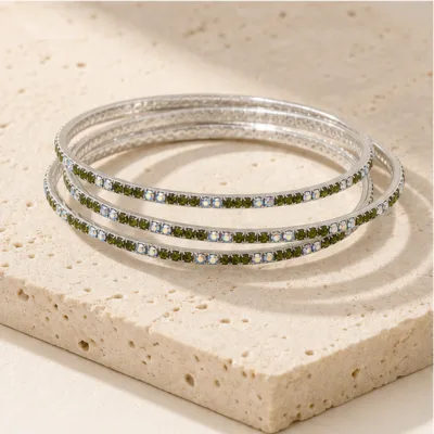 Pulseiras prateadas com cristais verdes e iridescentes numa composição elegante