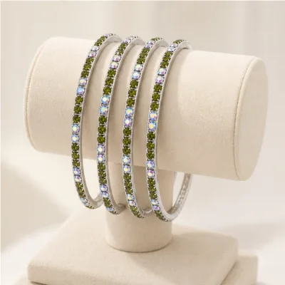 Quatro pulseiras prateadas com cristais verdes e AB num expositor