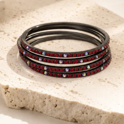 Pulseiras gunmetal com cristais vermelhos e iridescentes numa composição elegante