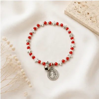 Pulseira religiosa vermelha e branca sobre tecido claro