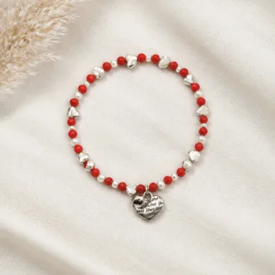 Pulseira vermelha e branca com coração sobre tecido claro