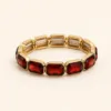 Pulseira elástica dourada com vidro vermelho facetado