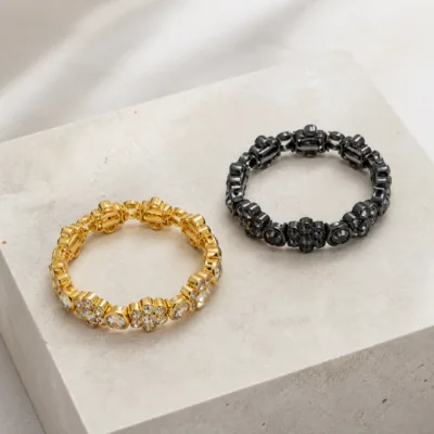 Pulseiras com cristais redondos dourada e preta sobre base clara