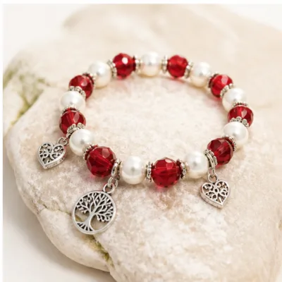 Pulseira vermelha de pérolas e cristais com árvore da vida sobre pedra clara