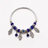 Pulseira de aro prateado com olho azul e pendentes de mãos da sorte