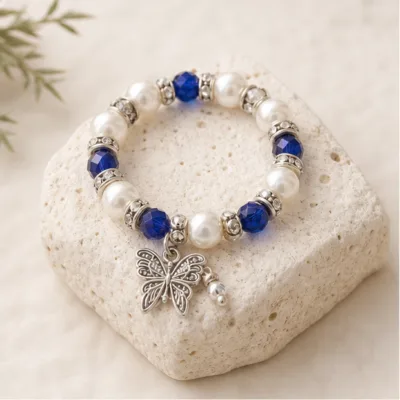 Pulseira azul de pérolas e cristais com borboleta sobre pedra clara