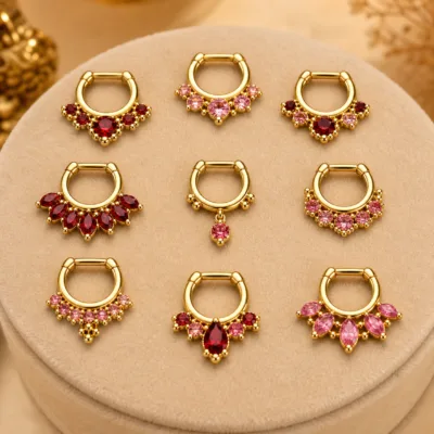 Detalhe dos piercings de septo dourados com zircónias vermelhas e rosa