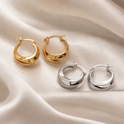 Brincos de argola com crescente em camadas dourados e prateados sobre seda neutra