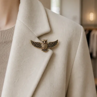 Alfinete de coruja dourado aplicado num blazer creme
